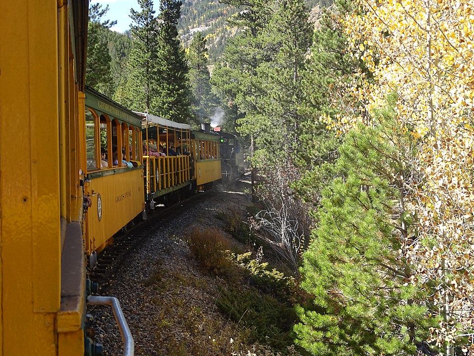 Historic narrow gauge train crossing a tall bridge in mountain canyon