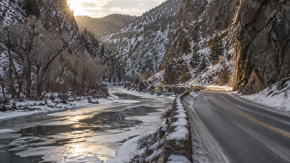 Two-lane canyon highway beside a partly frozen river in the Colorado front range in winter