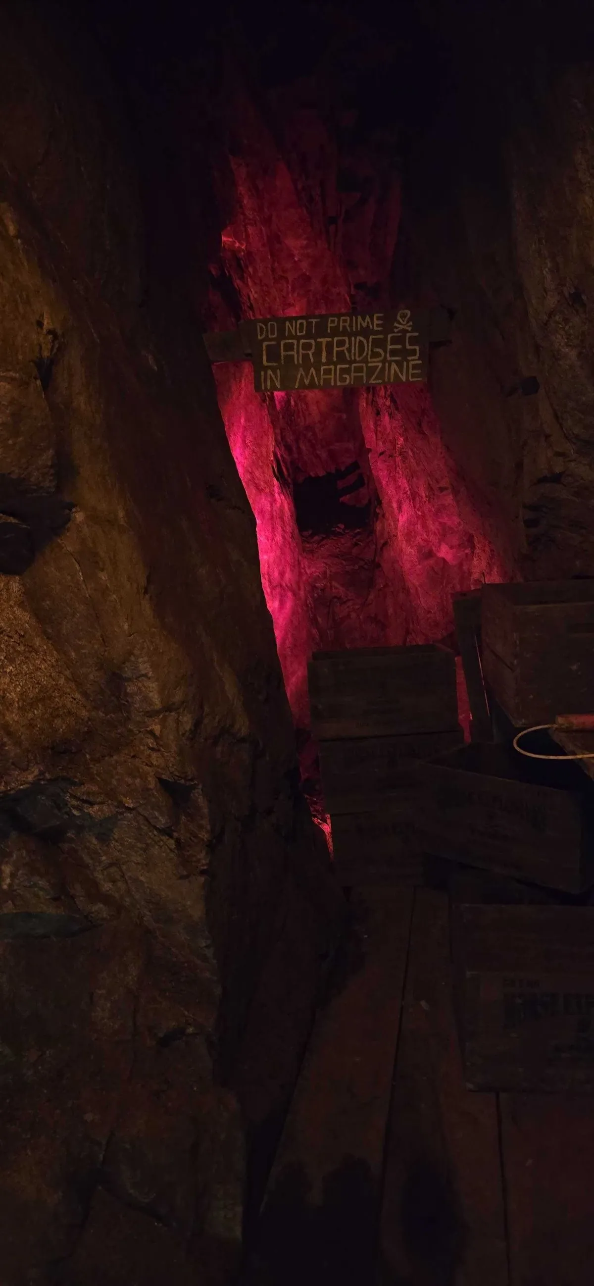Original warning sign — Do Not Prime Cartridges in Magazine — with skull and crossbones, lit in red inside the Lebanon Mine