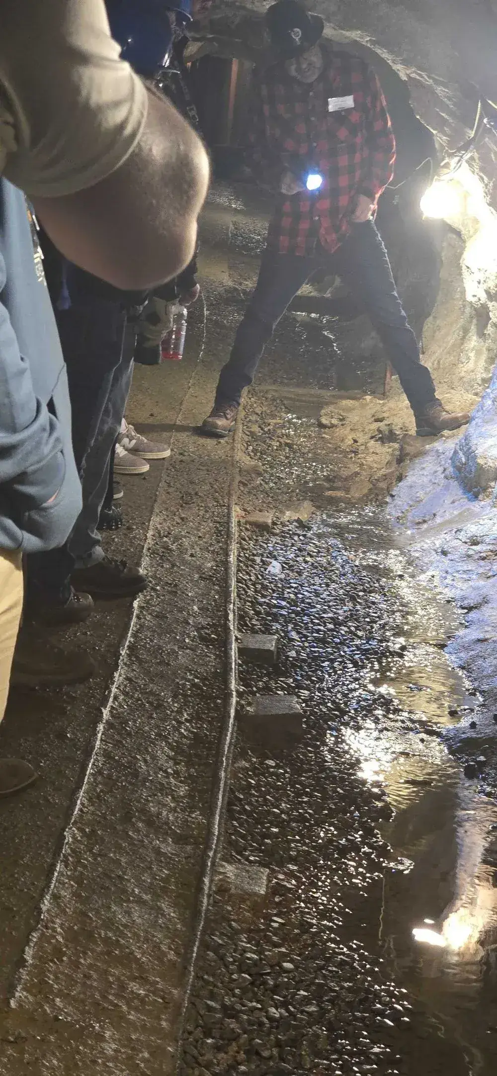 Tour guide standing on original mine cart tracks inside the Lebanon Mine, water pooling between the rails