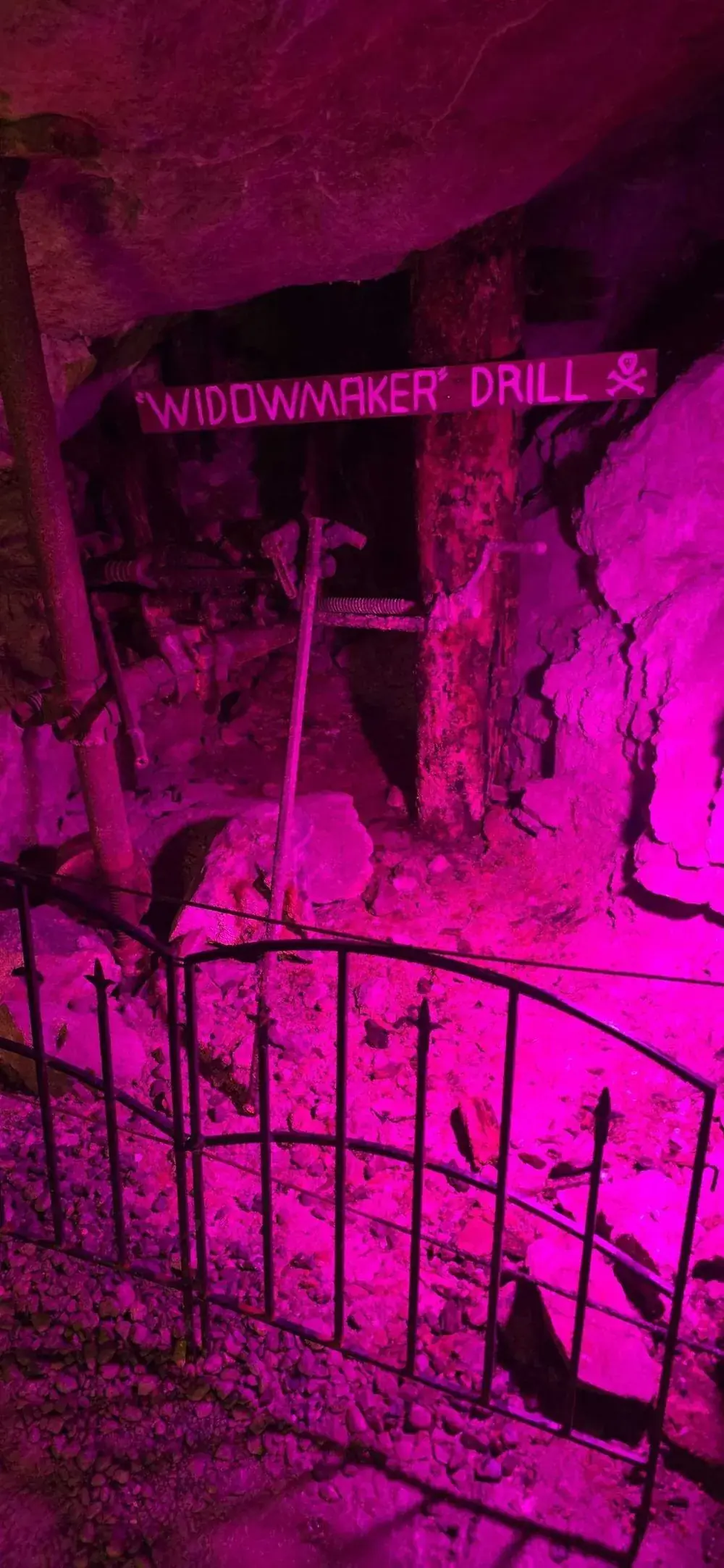 The Widowmaker drill display inside the Lebanon Mine, lit with purple light, skull and crossbones on the sign