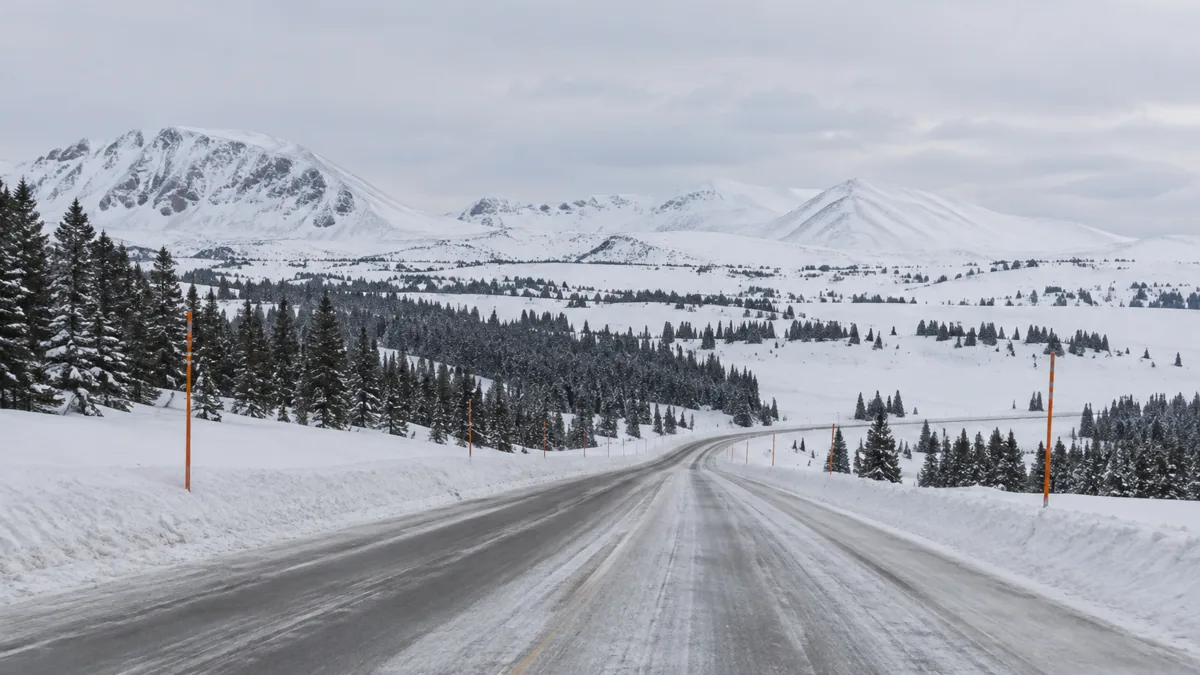 Snow-covered highway across the high plateau of Rabbit Ears Pass with orange snow poles