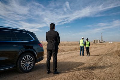Black SUV parked on a dirt county road on the Colorado plains near an oilfield site